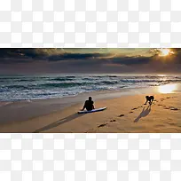 夕阳下沙滩上的人和狗
